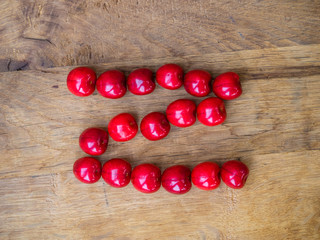 cherry on wooden background as a letter