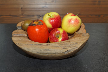 Scene of fruits in a wooden bowl on dark table