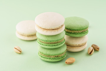 Stack of pistachio macarons on green background.