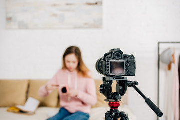 Naklejka premium Selective focus of teenage blogger sitting in front of video camera