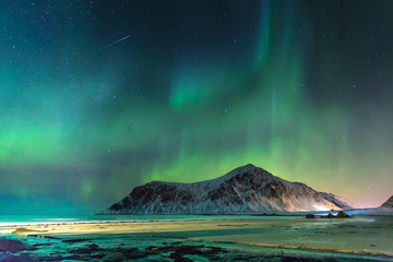 Fototapeta na wymiar Northern lights at night in the beg lonely beach with big mountains