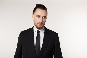 Half length portrait of beautiful brunette bearded guy with trendy hairdo in black suit