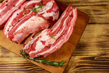 Raw pork ribs with spices and rosemary on wooden table. Top view