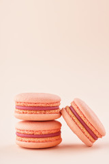 Stack of pink macarons on same color background.