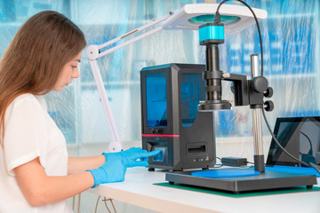 Woman worker in control of Resin LCD / DLP / SLA 3D Printer in technology lab