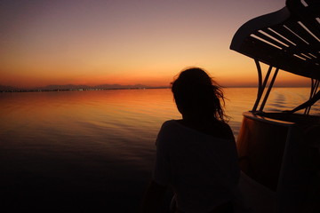 Fototapeta na wymiar Mädchen bei Sonnenuntergang auf dem Boot