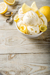 Homemade lemon vanilla ice cream with fresh lemon slices. Sweet and sour summer dessert. Wooden background copy space