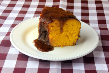 slice of carrot cake with chocolate coating on white ceramic plate on rustic wooden table