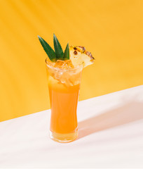 iced pineapple punch cocktail in glass on orange background. summer drink.