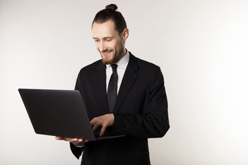 Young handsome businessman with beard and trendy hairstyle wearing black suit and tie