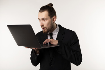 Serious bearded businessman or teacher in black suit reading post at notebook