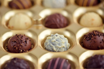 Assorted of chocolate candies in gold gift box. Selective focus