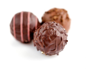 Three candies of black chocolate on white background. Selective focus