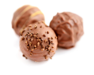 Three candies of milk chocolate on white background. Selective focus