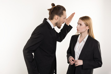 Attractive businessman with beard and trendy hairstyle in black suit screaming at his subordinate...