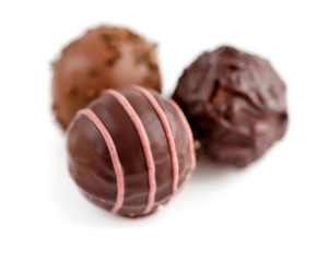 Three candies of black chocolate on white background. Selective focus