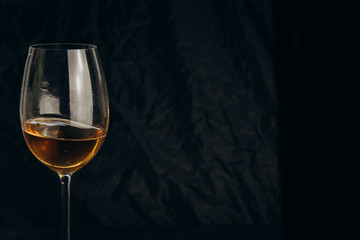 cropped female hand holding a glass of white wine on a black background. rest, holiday, party. isolated alcoholic drink closeup.