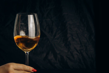 Obraz na płótnie Canvas cropped female hand holding a glass of white wine on a black background. rest, holiday, party. isolated alcoholic drink closeup.