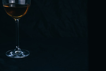 cropped glass of white wine on a black background. rest, holiday, party. isolated alcoholic drink closeup.