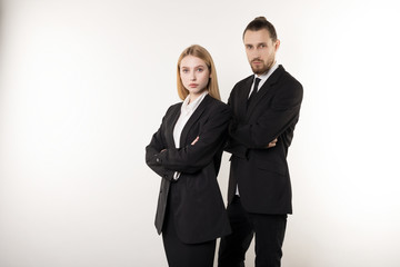 Confident serious businesspeople posing in black suits, standing with crosed hands, looking at camera