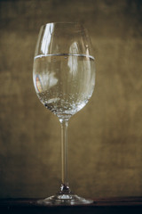 cropped glass of white wine on a rustic wooden brown background. rest, holiday, party. alcoholic drink closeup. copy space