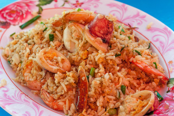 Seafood Fried rice with shrimp, squid, crab, vegetables on the dish thai style on blue table at restaurant. Thai style.