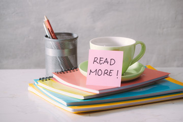 Green cup, notebooks and sticker with text - Read more on light background. Toned business concept with copy space