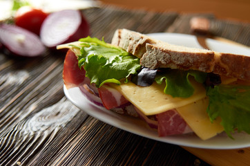 Sandwich with bacon, cheese and herbs on a plate