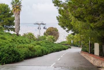 Perspective view of the road on Montjuic mountain, Montjuic Cable Car and Barcelona city from a height in overcast day, Spain