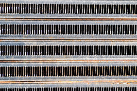 The old metal grille. Rusty textured background. Details and parts of the technique. Small oblong holes in a large number.