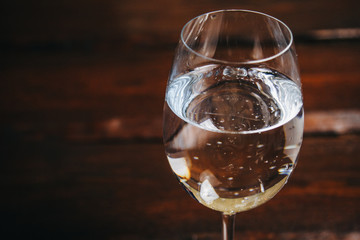 cropped glass of white wine on a rustic wooden brown background. rest, holiday, party. alcoholic drink closeup. copy space