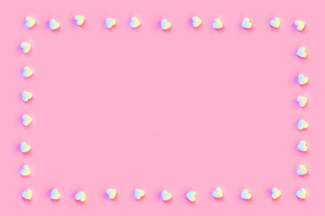 Square frame made of small white sugar candy hearts on a pastel living coral color paper