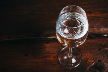 A glass of white wine on a rustic wooden red background. rest, holiday, party. crystal glass closeup. copy space. top view