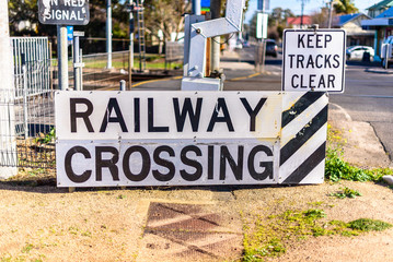 A large 'Railway Crossing' reflective road sign, with a smaller 'Keep Tracks Clear' sign above it. - obrazy, fototapety, plakaty