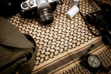camera film compass and passport with shemagh scarf on wooden table. travel equipment. copy space. reto style.