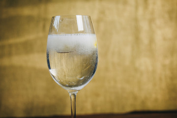 A glass of homemade lemonade with ice and lime on a rustic wooden brown background. rest, holiday, party. crystal glass closeup. copy space