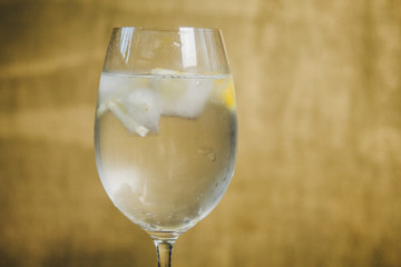 A glass of homemade lemonade with ice and lime on a rustic wooden brown background. rest, holiday, party. crystal glass closeup. copy space