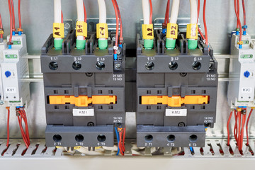 Electrical cables and wires are connected to two powerful magnetic starter or contactor. On the sides of the modular time relay with adjustment. Electrical equipment in the electrical Cabinet.