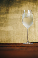 A glass of homemade lemonade with ice and lime on a rustic wooden brown background. rest, holiday, party. crystal glass closeup. copy space
