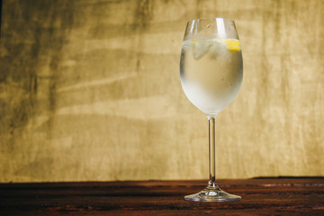 A glass of homemade lemonade with ice and lime on a rustic wooden brown background. rest, holiday, party. crystal glass closeup. copy space