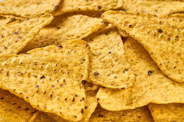 The background of yellow triangular corn nachos close-up
