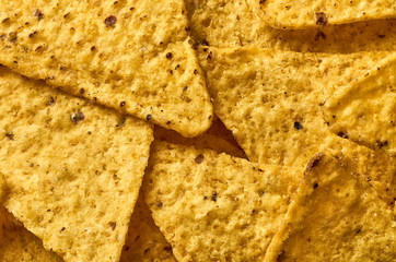The background of yellow triangular corn nachos close-up