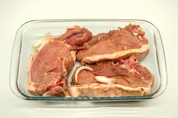 Marinated fresh large pieces of pork, sprinkled with spices for a barbecue in a glassware