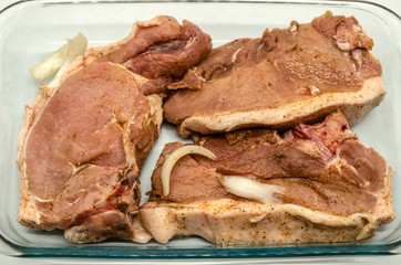 Sliced in large portions for barbecue and marinated pork with onions and spices in a glassware