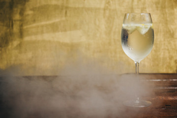 A glass of homemade lemonade with ice and lime on a rustic wooden brown background. rest, holiday, party. crystal glass closeup. copy space