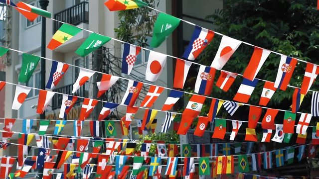 Flags of different nations fluttering in the wind, slow motion. Symbols of the countries are suspended in the air