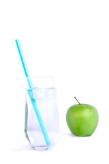 Close up of green organic apple and glass of water on white table. Healthy eating diet concept, selective focus