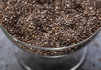 Chia seeds in a glass vase close-up. The texture of the seeds. Horizontal.