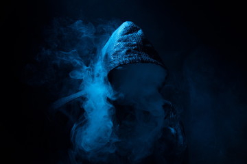 Black hood and smoke.The concept "smoking kills".Drug Addiction.Cannabis smoking.Black background. - Powered by Adobe