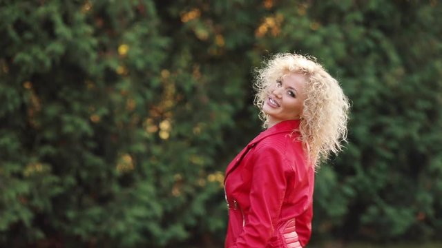 Cute blond girl is tyding her curly hair